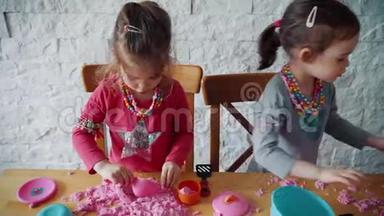 两个小女孩在桌子上玩动能沙